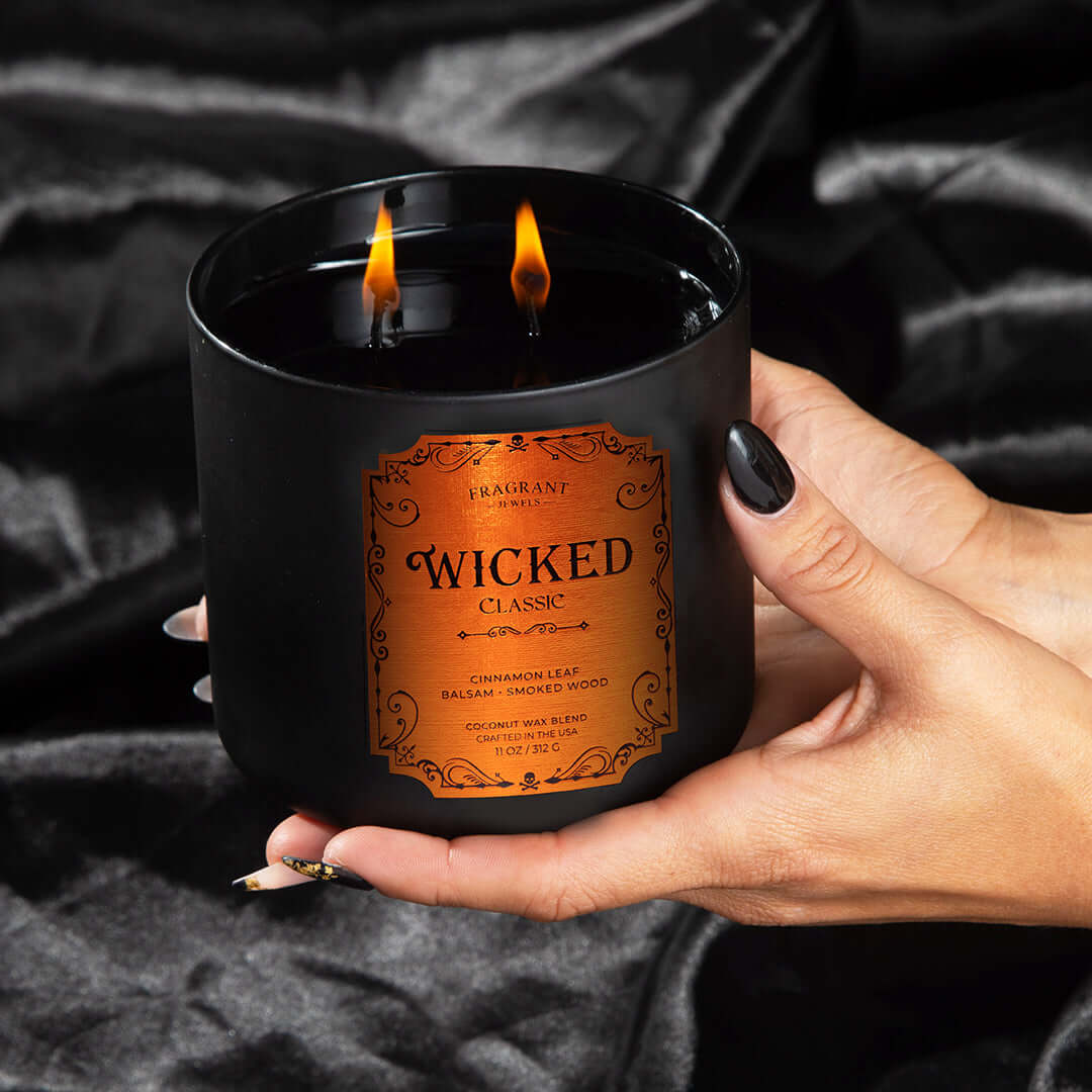 Wicked Classic Jewel Candle - Experience Dark Magic in a dark jar with an orange label, featuring cinnamon leaf and smoked wood.