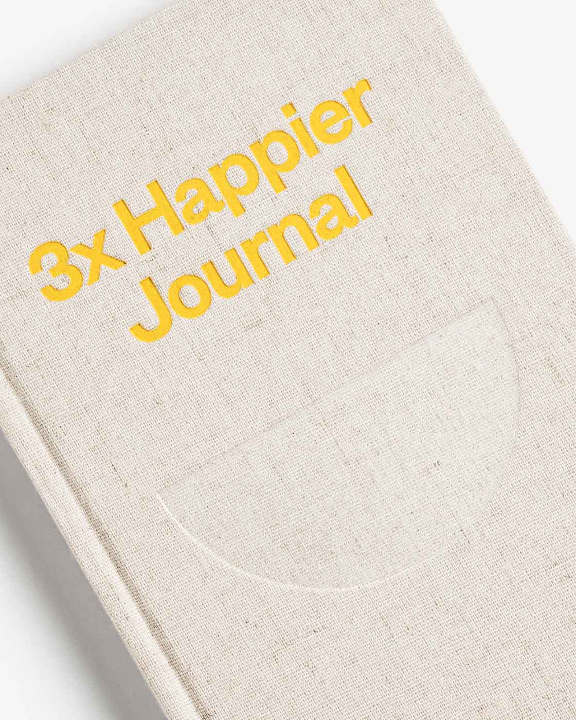 Close-up of the Intelligent Change 3x Happier Journal with a soft cover and pages open, showcasing its design and layout.