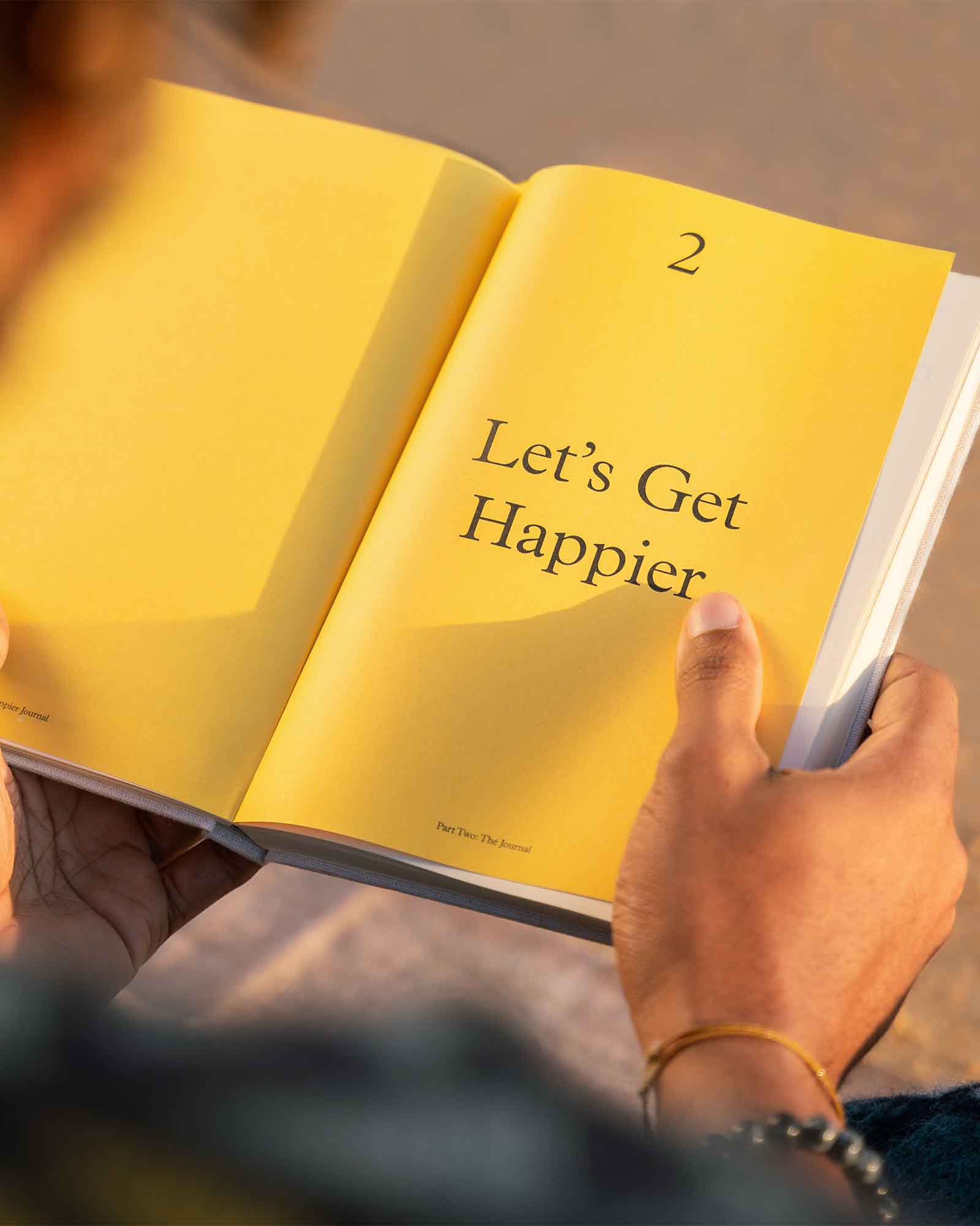 A 3x Happier Journal by Intelligent Change featuring a hardcover journal with motivational prompts and a minimalist design.
