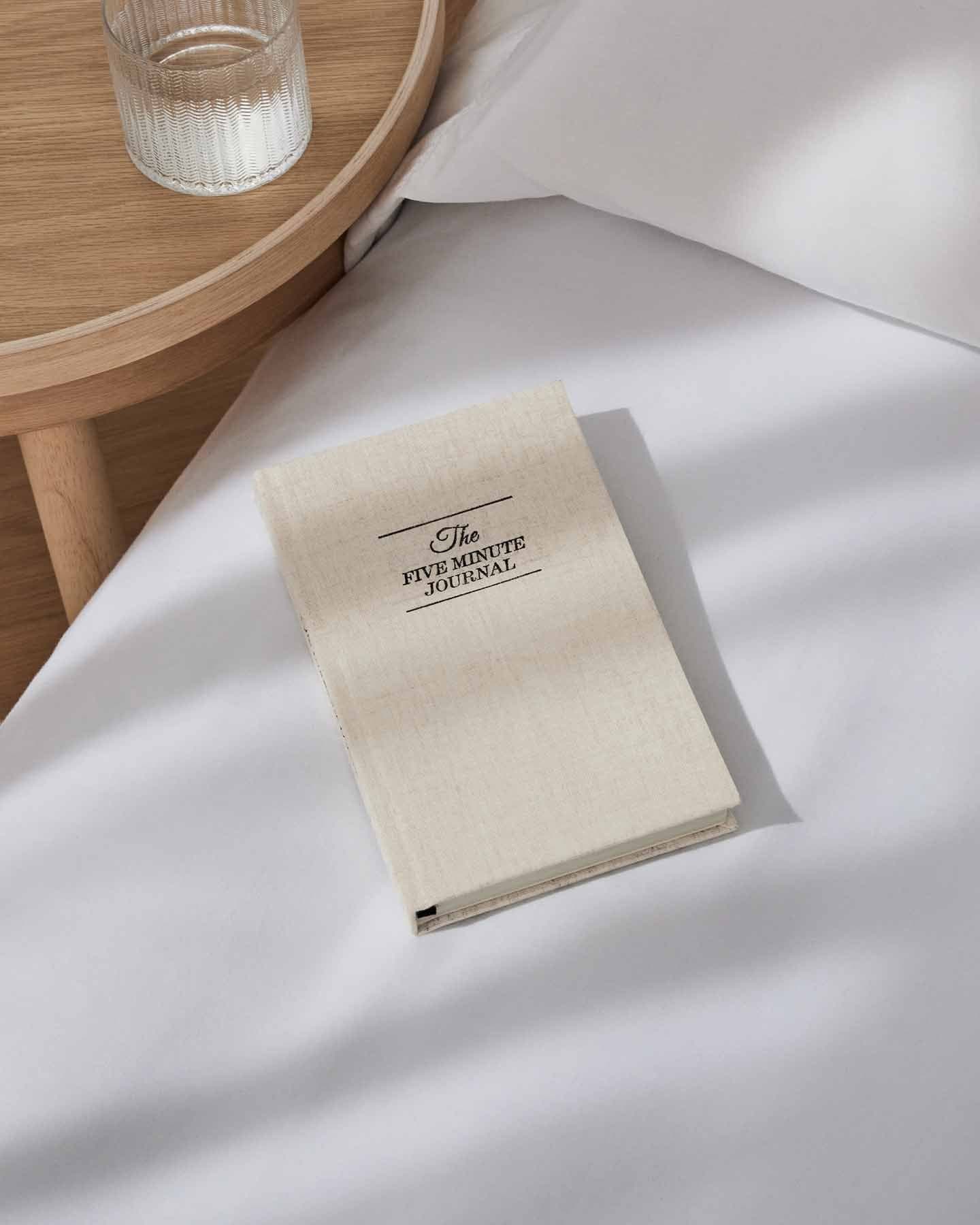 The Five Minute Journal Original Linen mindfulness journal by Intelligent Change, featuring a soft linen cover and neatly arranged pages.